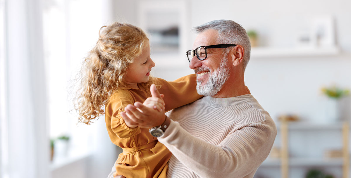an older man wearing glasses having trouble seeing his laptop screen at home