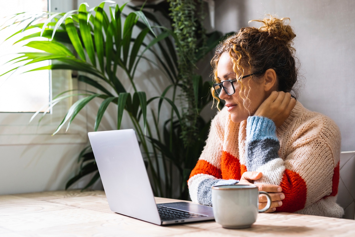 woman sitting at a table and looking at her computer