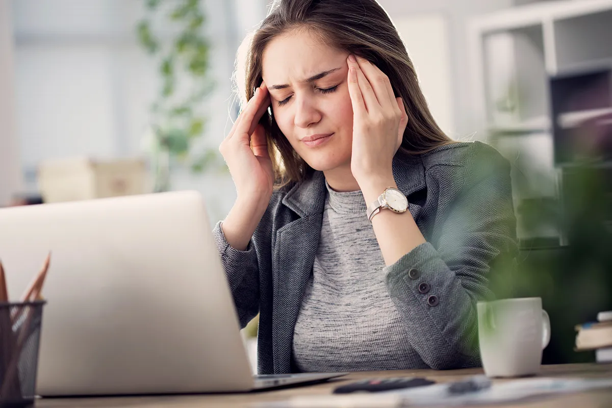 a woman touching her face and looking uncomfortable while working on a computer